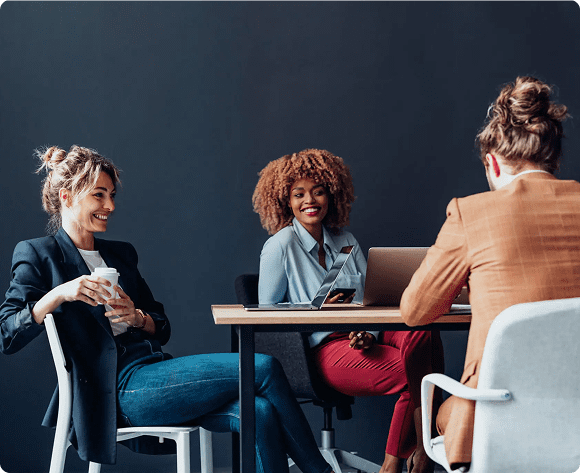 Three colleagues engaged in a lively meeting around a table.