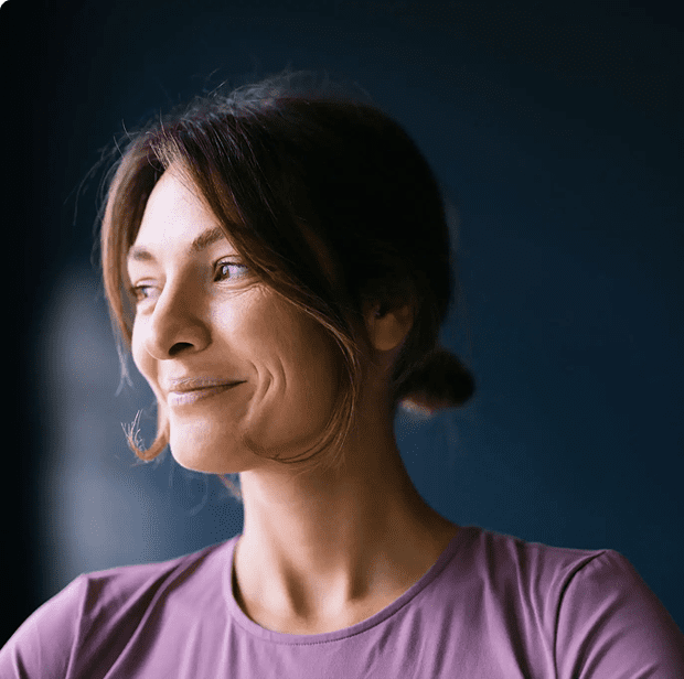 Thoughtful woman looking out a window with a gentle smile.